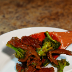 beef and broccoli ibeing plated in a bowl
