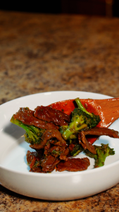 beef and broccoli ibeing plated in a bowl