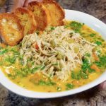 Chicken Noodle Soup in a bowl with crustinis and topped with parsley