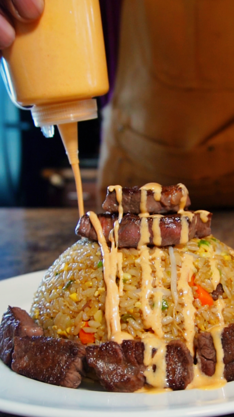pouring yum yum sauce over steak fried rice