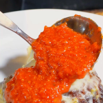 pouring homemade marinara sauce over chicken parm