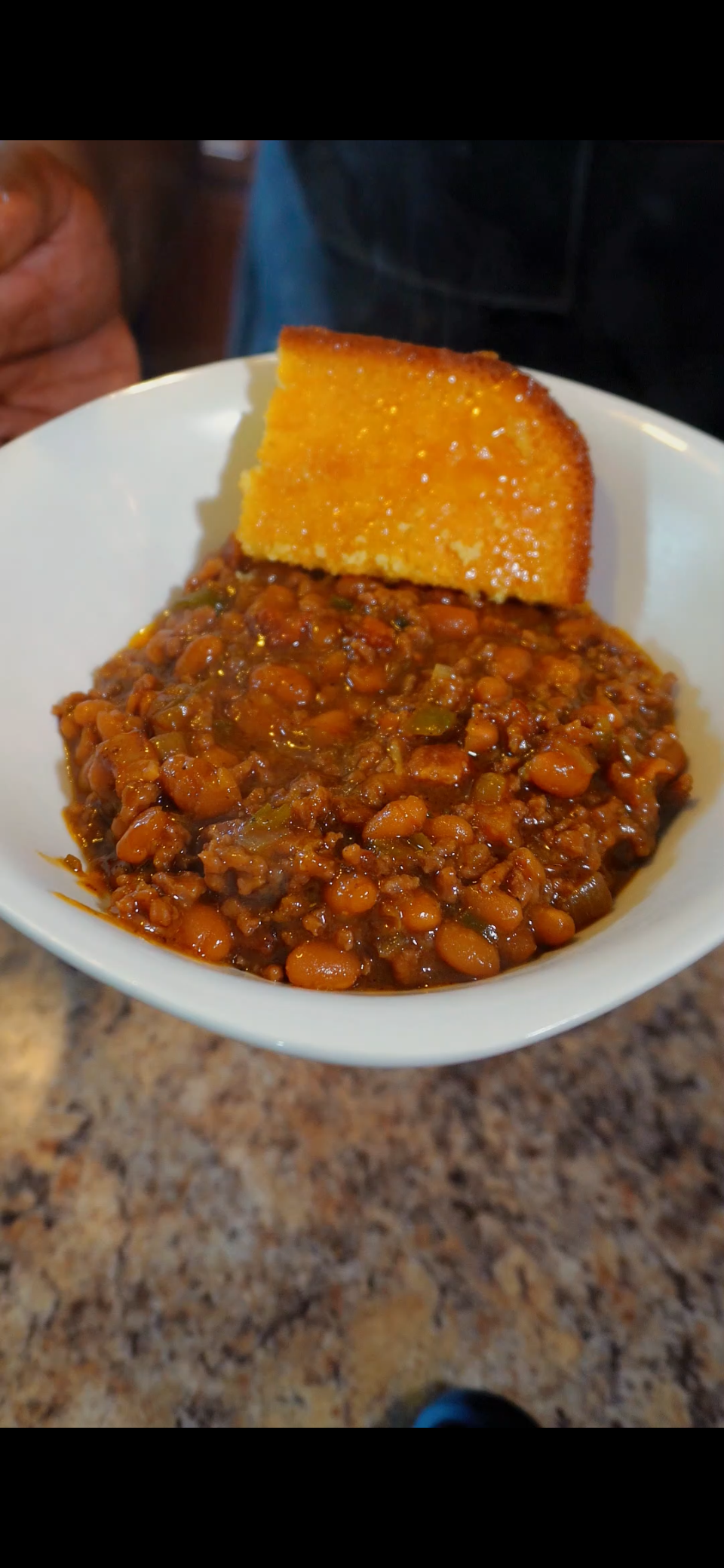 Baked beans in bowl with cornbread on side
