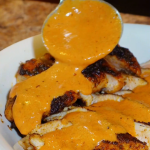 blackened chicken with dirty rice and cream sauce being poured