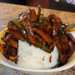pepper steak being plated over white rice