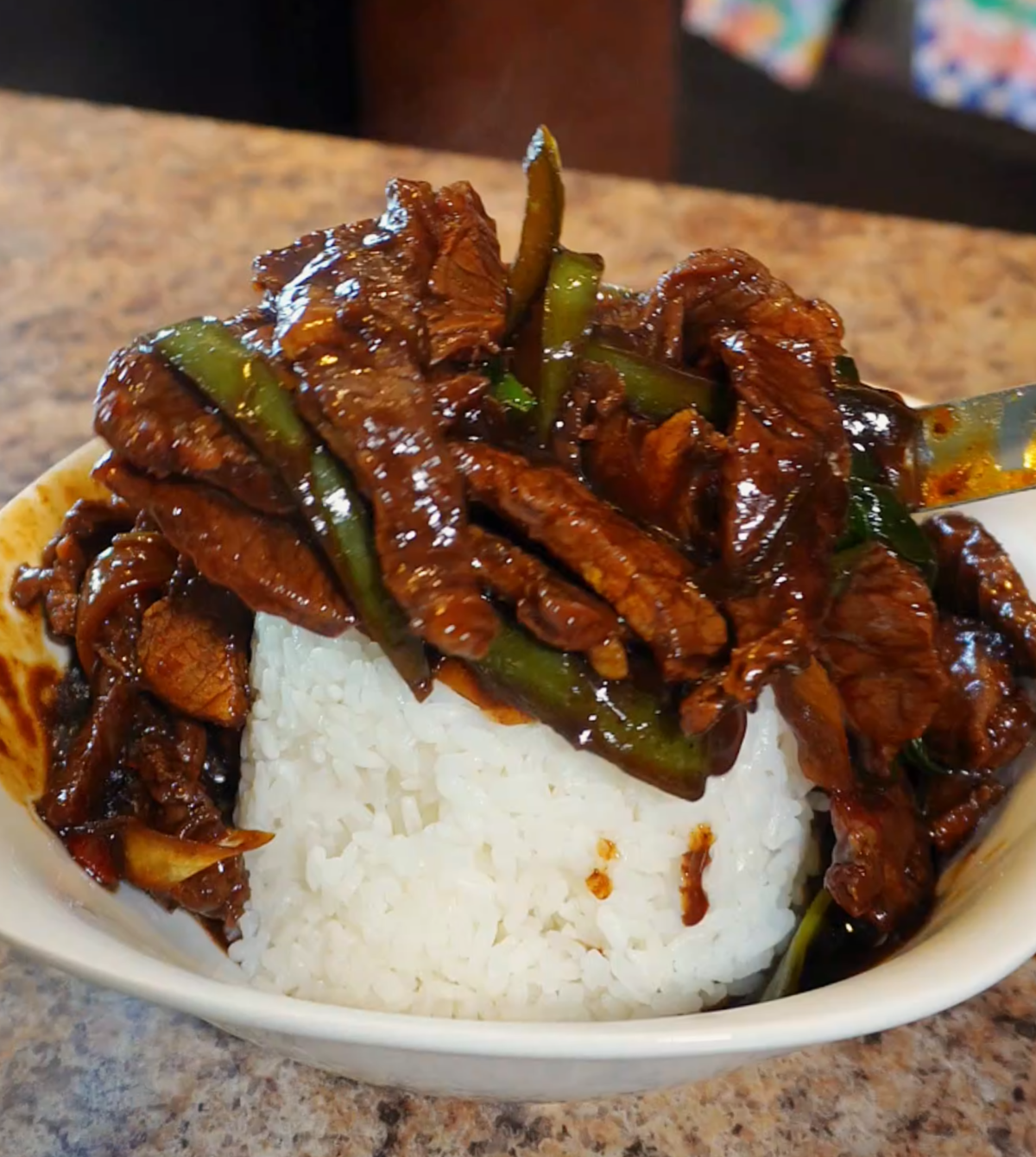 pepper steak being plated over white rice
