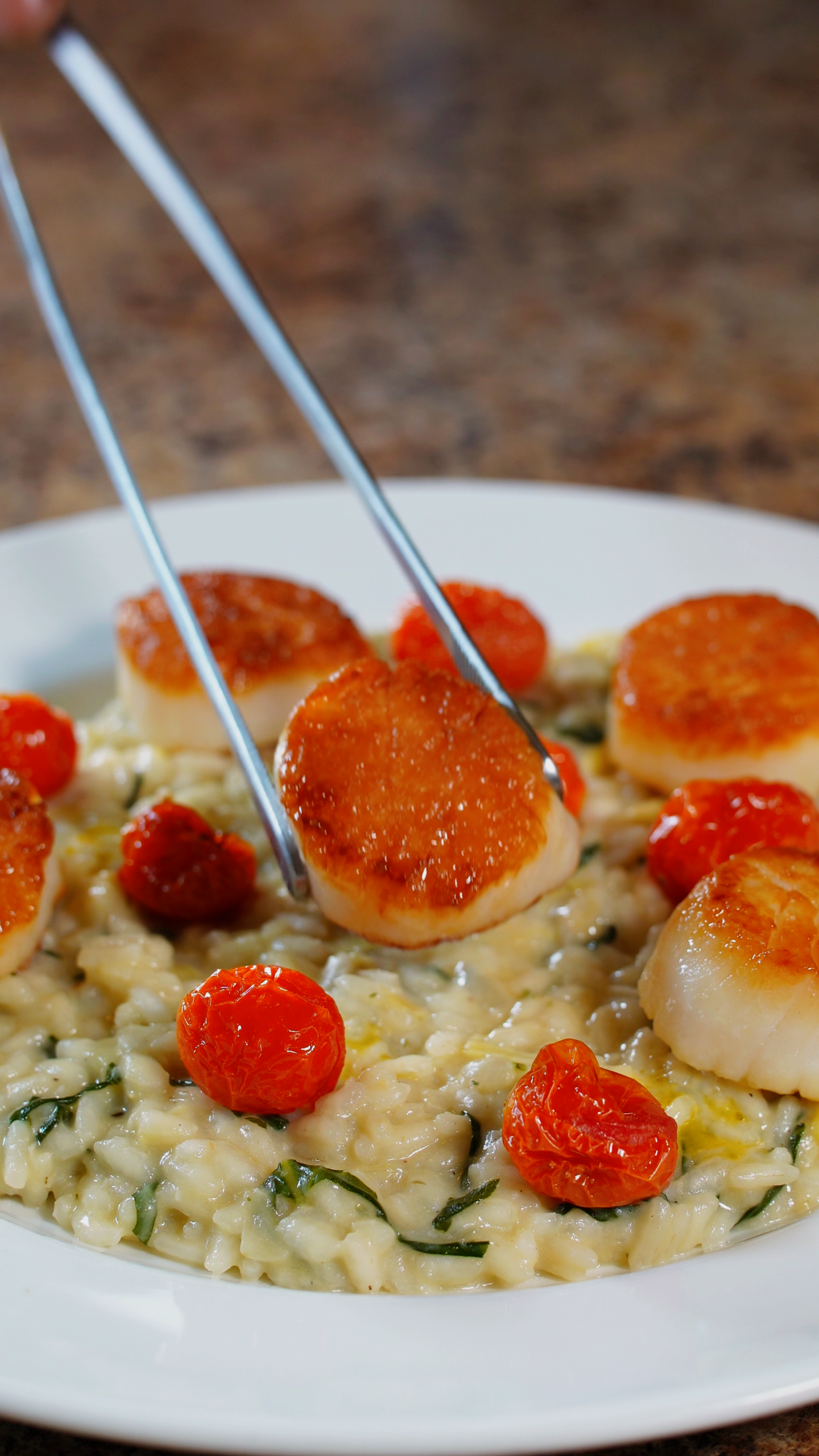 scallop placed on top of spinach and artichoke risotto