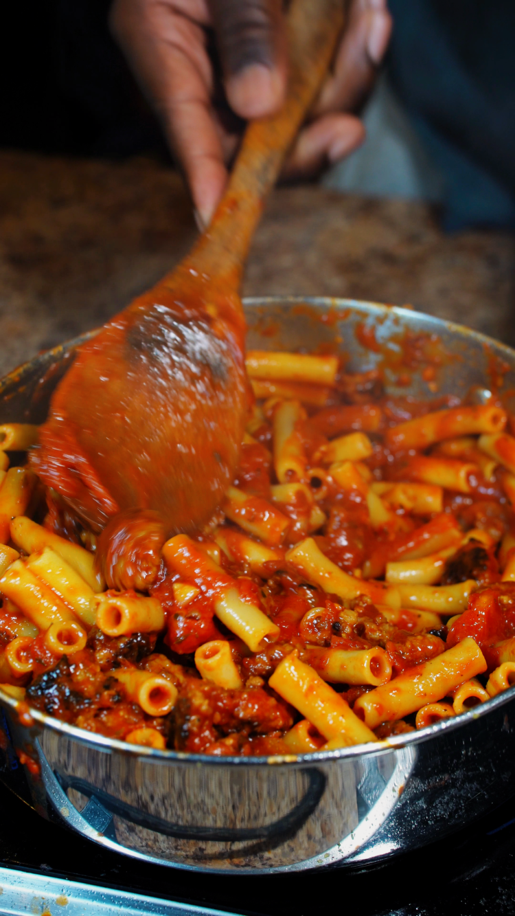 stirring sausage ziti in a pot