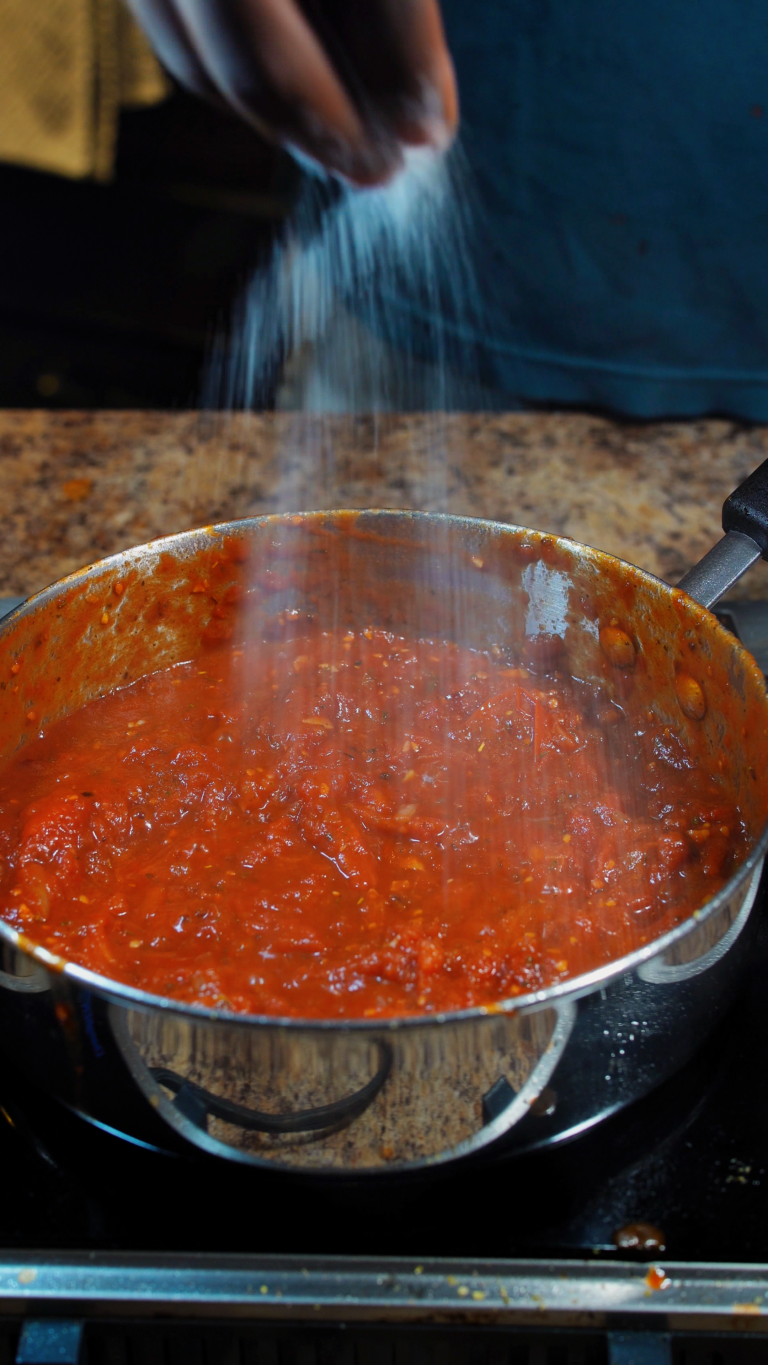 sprinkling salt into pasta sauce